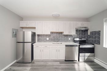 A kitchen with white cabinets and a stainless steel refrigerator